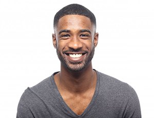 young man wearing black V-neck shirt and smiling against white background 