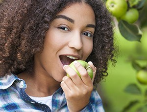 Teen girl eating a green apple