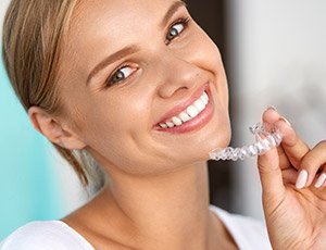 Young woman holding Invisalign clear aligner