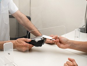 Closeup of patient using credit card to pay for dental treatment