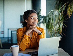 Woman in orange shirt smiling while sitting at desk in office