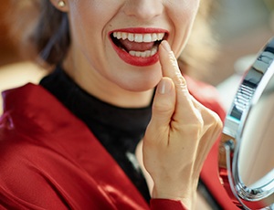 Woman smiling and pointing to a dental crown in Carrollton