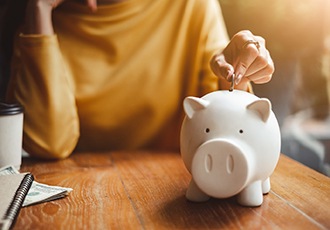 Someone putting coins into a piggy bank