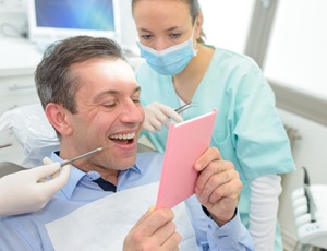 A man looking into the mirror at his new smile