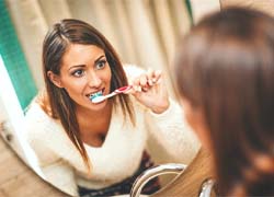 Woman brushing her teeth in Carrollton