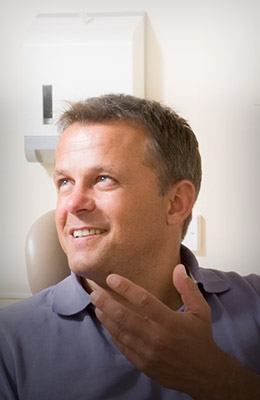 Man sitting in dental chair talking to dentist