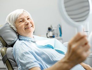 older woman smiling in dental chair after getting tooth-colored fillings in Carrollton 