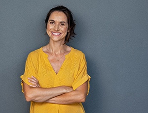 Woman in yellow shirt smiling with her arms crossed