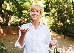 Woman tossing a green apple while walking outside