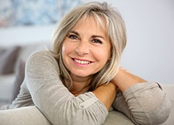 Woman with grey hair wearing grey shirt while smiling