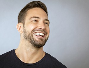 Man in black shirt smiling with grey background