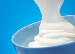 Close up of plain white yogurt with blue background