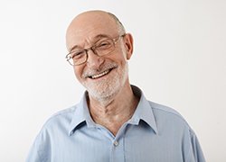 Older man with glasses and collared shirt smiling