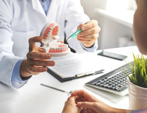 dentist pointing to a pair of dentures