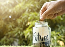 hand putting coins into a glass jar that says future