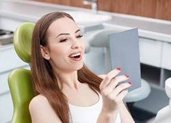 young woman looking at her smile in a mirror