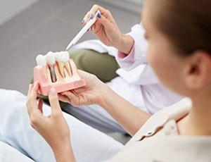 dentist showing a patient a dental implant model