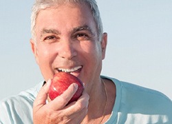 man biting into a red apple