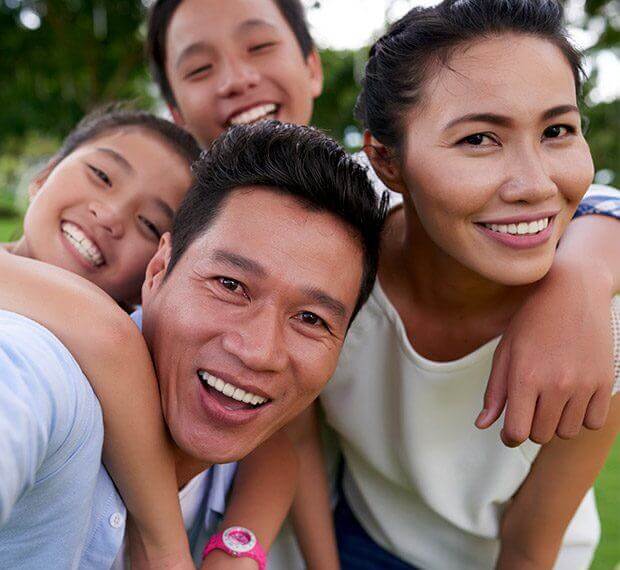 Mother father and two children smiling outdoors