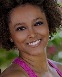 Woman wearing magenta sleeveless top and grinning outdoors