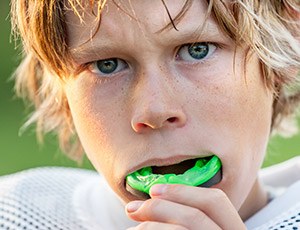 Teen boy placing green sports mouthguard