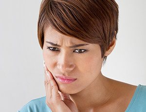 Woman holding cheek in pain