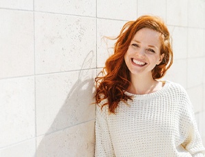 Woman in white sweater leaning against wall