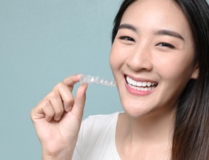 A young woman holding a clear aligner