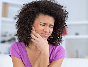 Woman in purple shirt with jaw pain from TMJ disorder in Carrollton, TX
