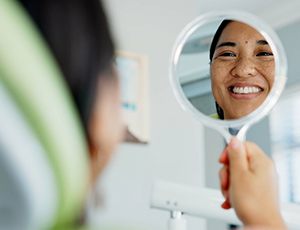Young female smiling in the mirror at dentist’s office