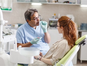 A dental patient sitting in the dentist chair talking to her dentist