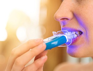 Woman shining light on her own teeth