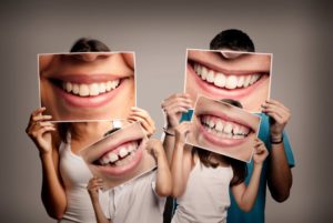 family holding smiles in front of their faces