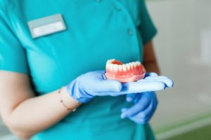 Closeup of dentist holding dentures in Carrollton 