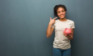 woman holding a piggy bank and pointing to her smile 