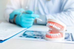 set of dentures in the foreground with a dentist's gloved hand in the background