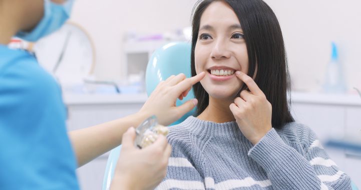 A woman pointing to her tooth at her dentist’s office