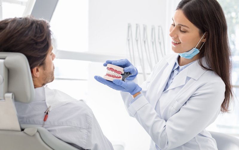 female dentist talking to younger male patient about dentures